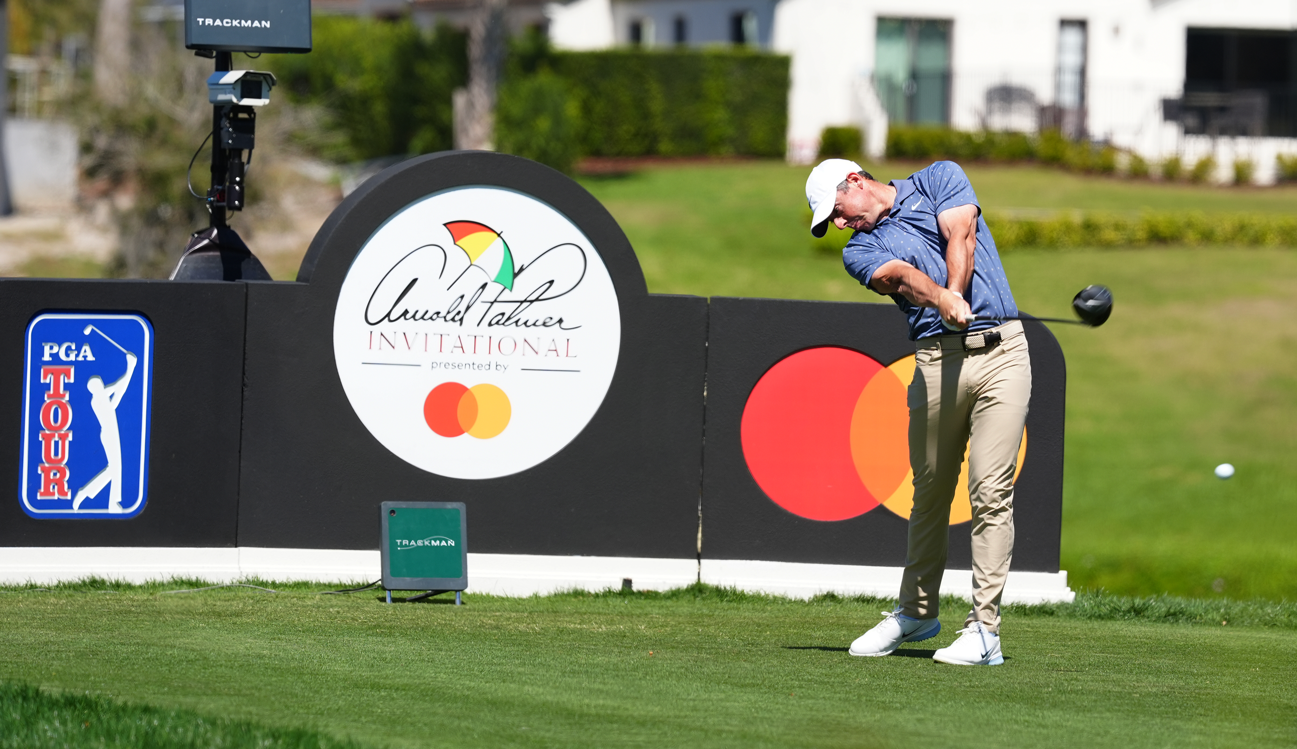 Rory McIlroy hits a tee shot in front of an Arnold Palmer Invitational board