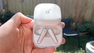 The Soundcore Liberty 5 earbuds outside in the sunlight and held by our reviewer, Katie Wickens.