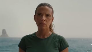 Jurassic World star Scarlett Johansson stands on a boat with the ocean as a backdrop wearing a t-shirt in the Rebirth trailer. 