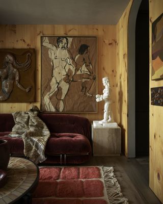 wood panelled room with red sofa and art
