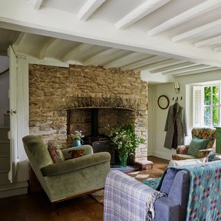 view towards fireplace in a beamed cottage living room furnished with vintage pieces