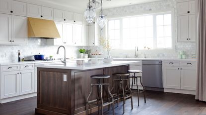 A 2015 kitchen with white cabinets, a wooden island, a brass range hood, and exposed appliances
