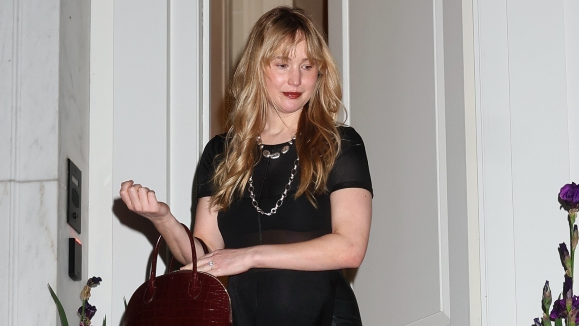 Actress Jennifer Lawrence attends an exclusive fashion event at the house of Lauren Santo Domingo, now owned by Ralph Lauren, in New York, looking chic in a black midi dress, burgundy handbag, and black pointed flats.