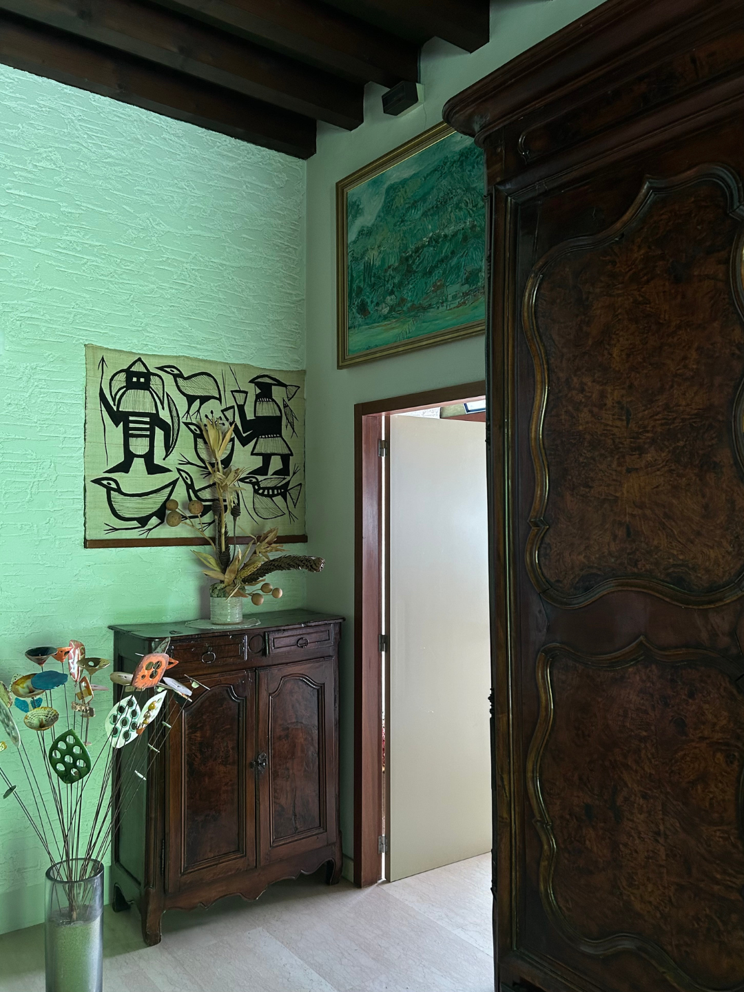 Roset family hallway with antique wood furniture, expressive art and sculptural objects collected over time.