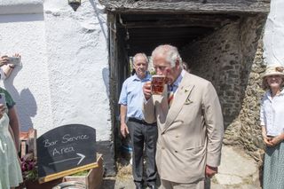 Prince Charles, Prince of Wales, drinks a pint of Bayes Topsail as he and Camilla, Duchess of Cornwall (not pictured) visit the Duke of York Public House in Devon