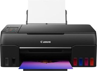 En svart Canon Pixma G620 som håller på att skriva ut en bild visas upp mot en vit bakgrund.