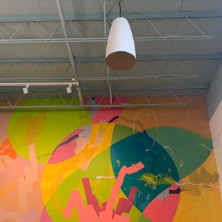 An LEA Professional pendant speaker hangs before a brightly colored wall in an Atlanta coffee shop.