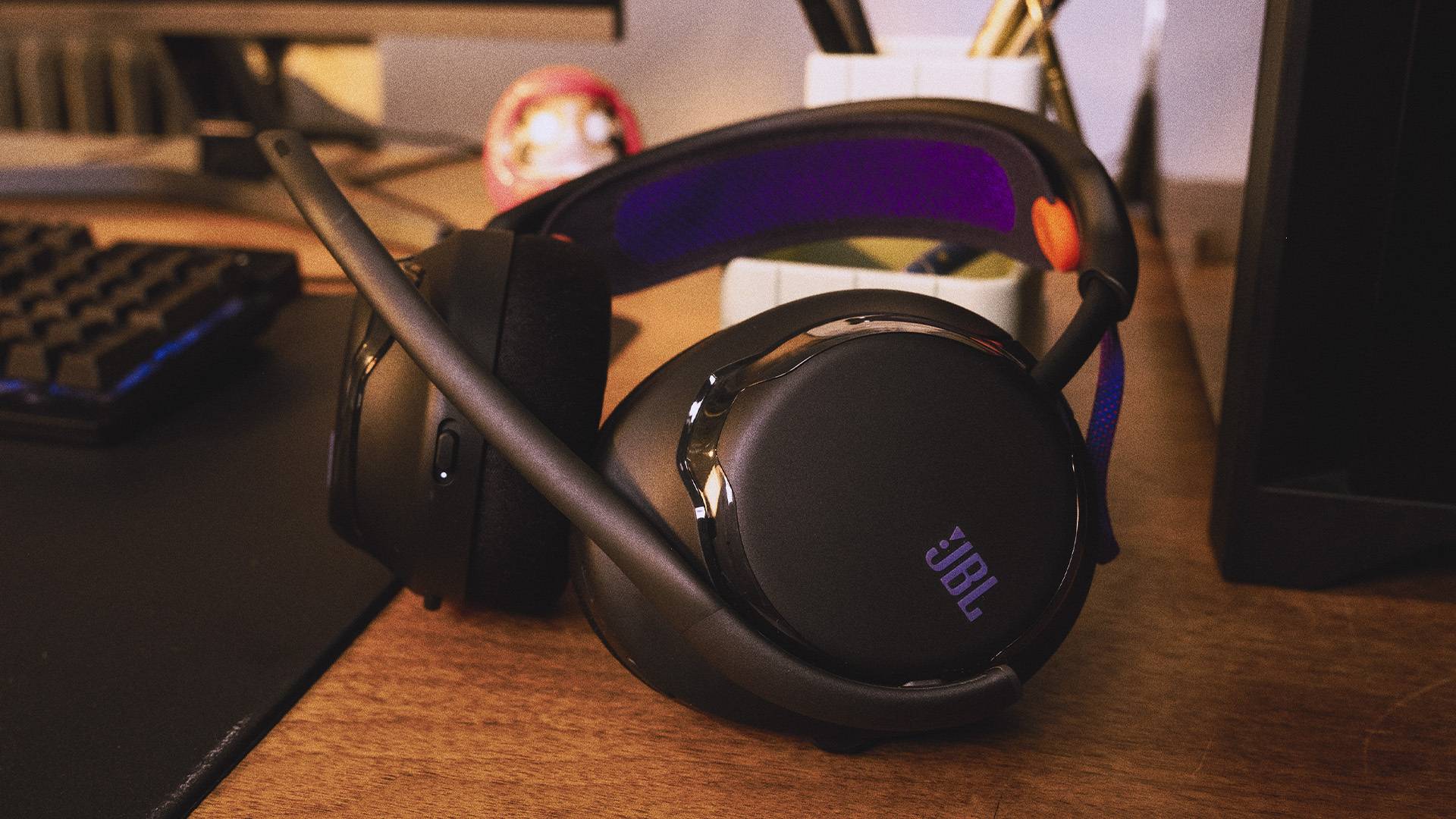 Image of a black and purple JBL gaming headset sitting on a wooden desk.