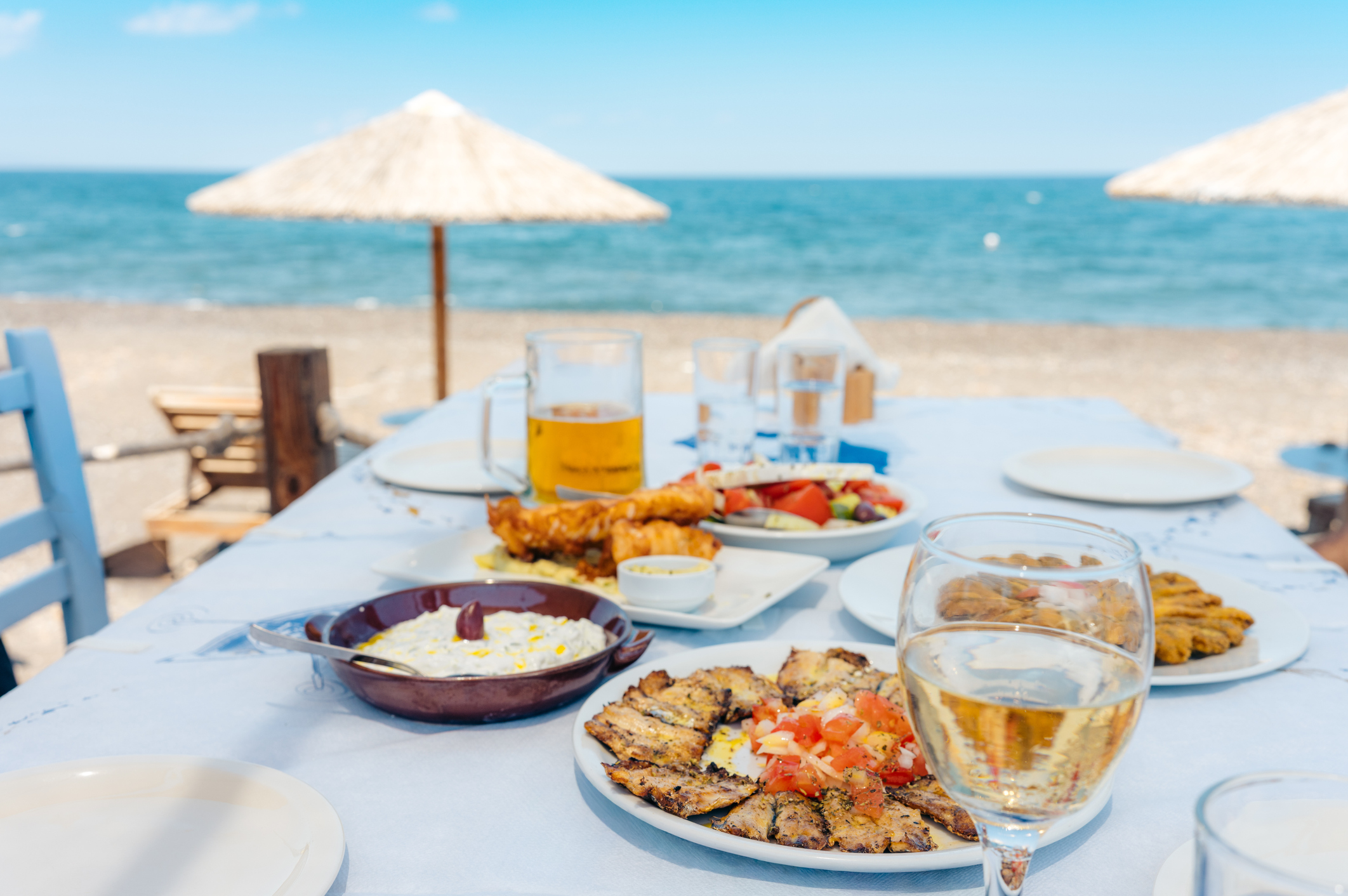 a dinner table filled with traditional Greek seafood and wine by the sea.