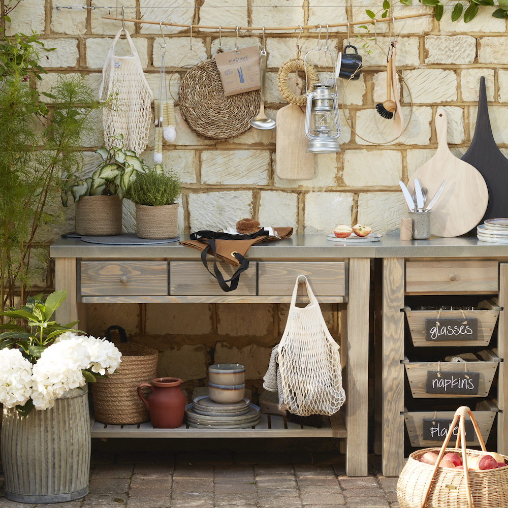 wooden outdoor kitchen alongside brick wall