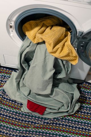 Washing machine with door open and clothes hanging out.