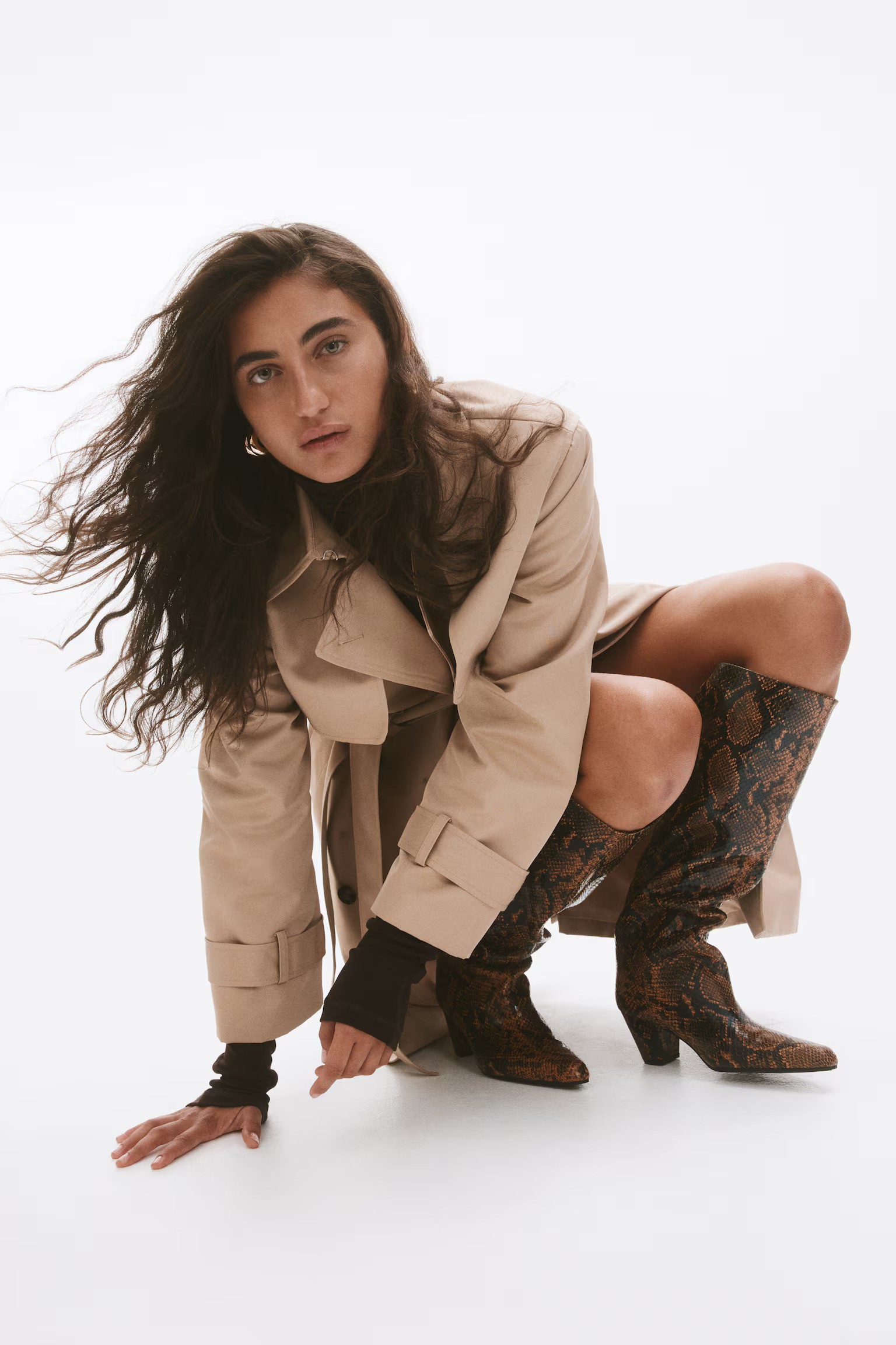 Woman wears trench coat and snake print boots