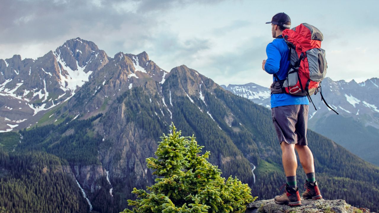 A man out hiking with his rucksack on and looking out towards the mountains