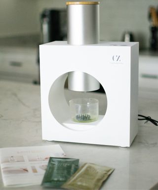 Cuzen matcha maker with instruction booklet and two sachets of whole leaf green tea on marble worktop in modern kitchen
