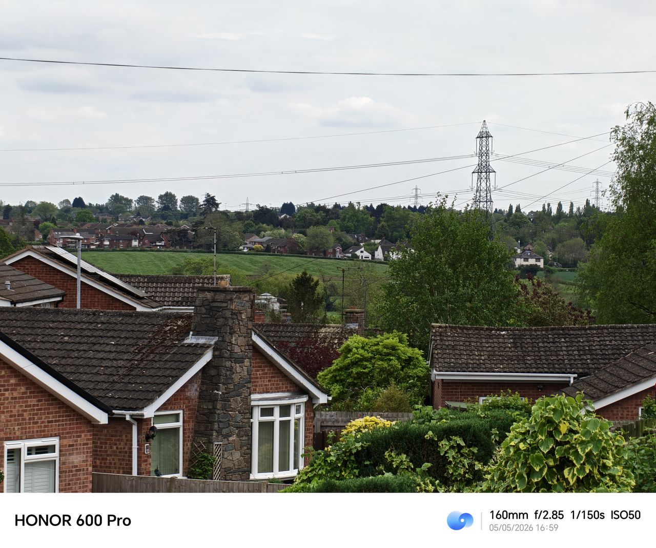 Telephoto view of rooftops, trees, and distant power lines from the Honor 600 Pro