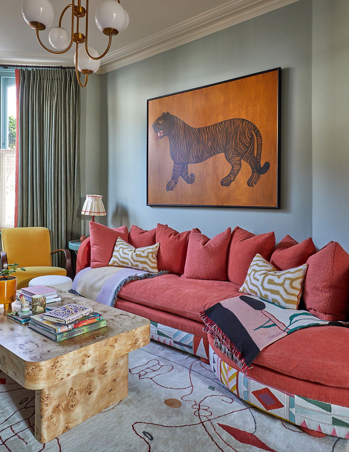 blue living room with pink sofa, burl coffee table, and tiger print artwork