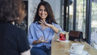 ASL: Image shows woman signing in cafe