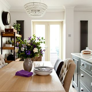 room with wooden table flower vase and white door