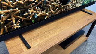 Philips OLED909 OLED TV showing bottom of screen and feet on wooden hi-fi bench