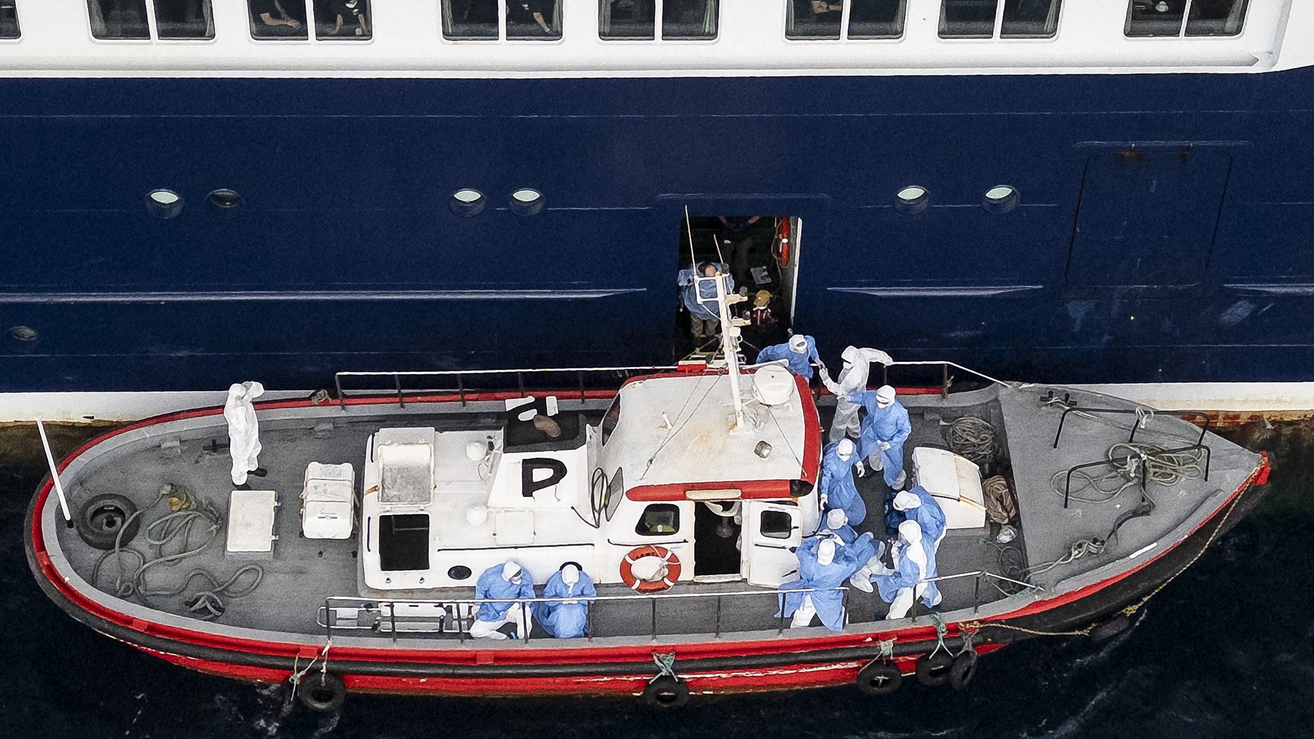 Health personnel assist patients onto a boat.