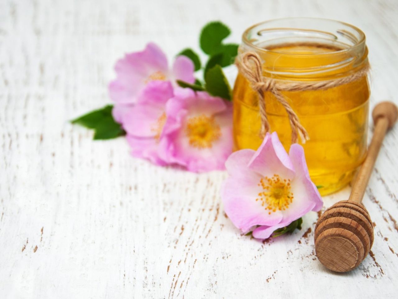 Pink Flowers Next To A Jar Of Honey