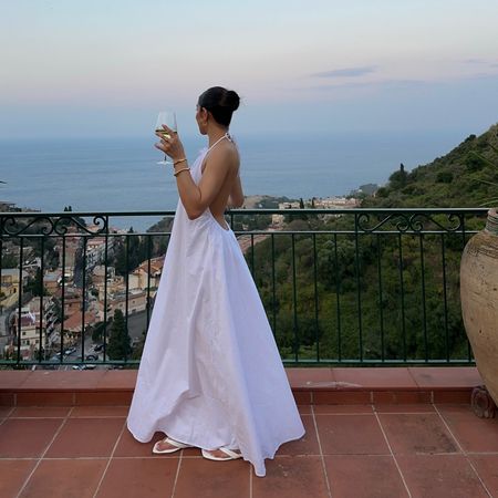 Photo of a woman drinking wine looking at the coastline 