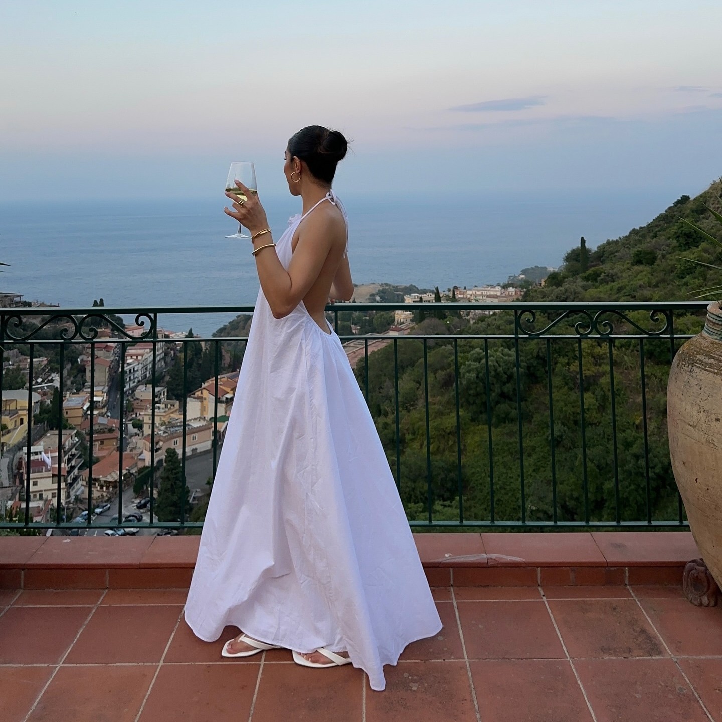 Photo of a woman drinking wine looking at the coastline 