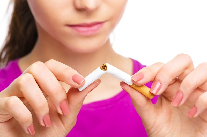 A woman breaks a cigarette into two.