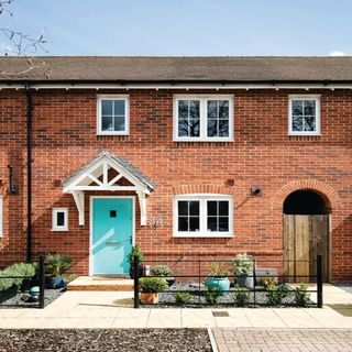 red brick mid terraced house with white windows and turquoise front door