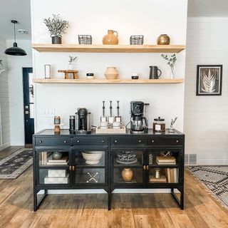 Smart coffee station area on black glazed sideboard, complete with coffee machines and accessories.