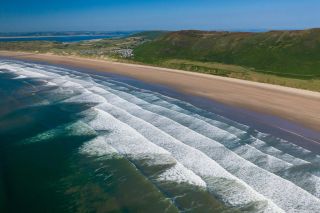 Aerial drone view of the beautiful, huge sandy beach at Rhossili on the Gower Peninsula in Wales