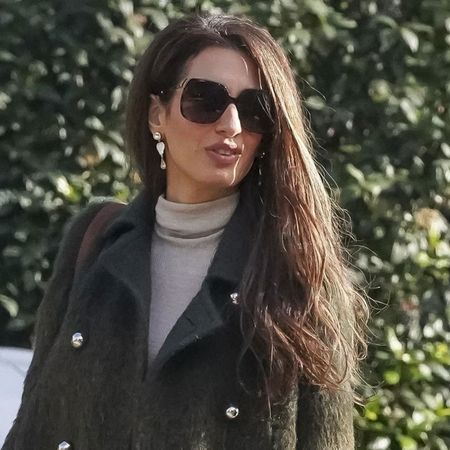 Amal Clooney wears a green coat and black tights in France in December 2025