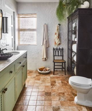 Brown tile floor, green sinks, black cabinet