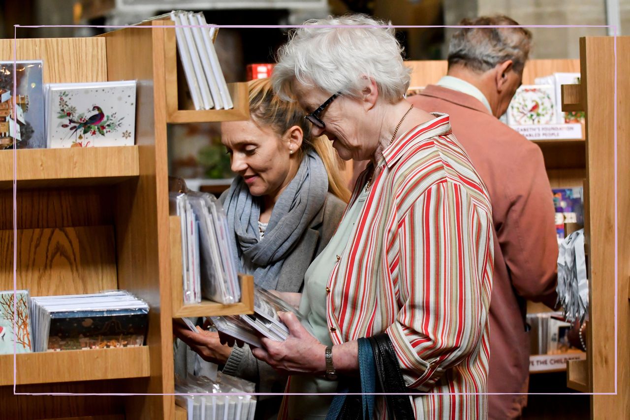 Two women looking at Christmas cards on the shelves of a Cards for Good Causes pop up shop