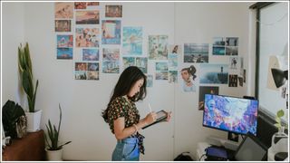 Young creative cartoonist is preparing her portfolio presentation and sketching her work in a digital tablet in front of her master piece work, Bangkok Thailand