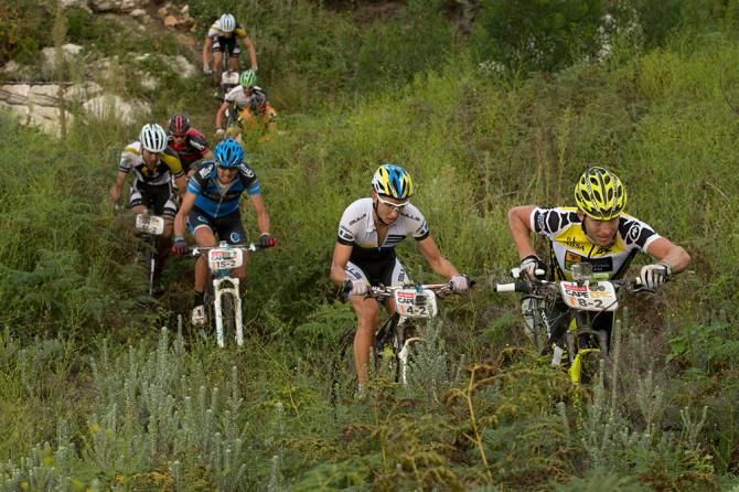 Kristian Hynek of Team Topeak-Ergon racing pushes his bike across a stream