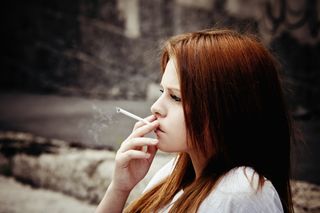 A teenage girl smokes a cigarette.