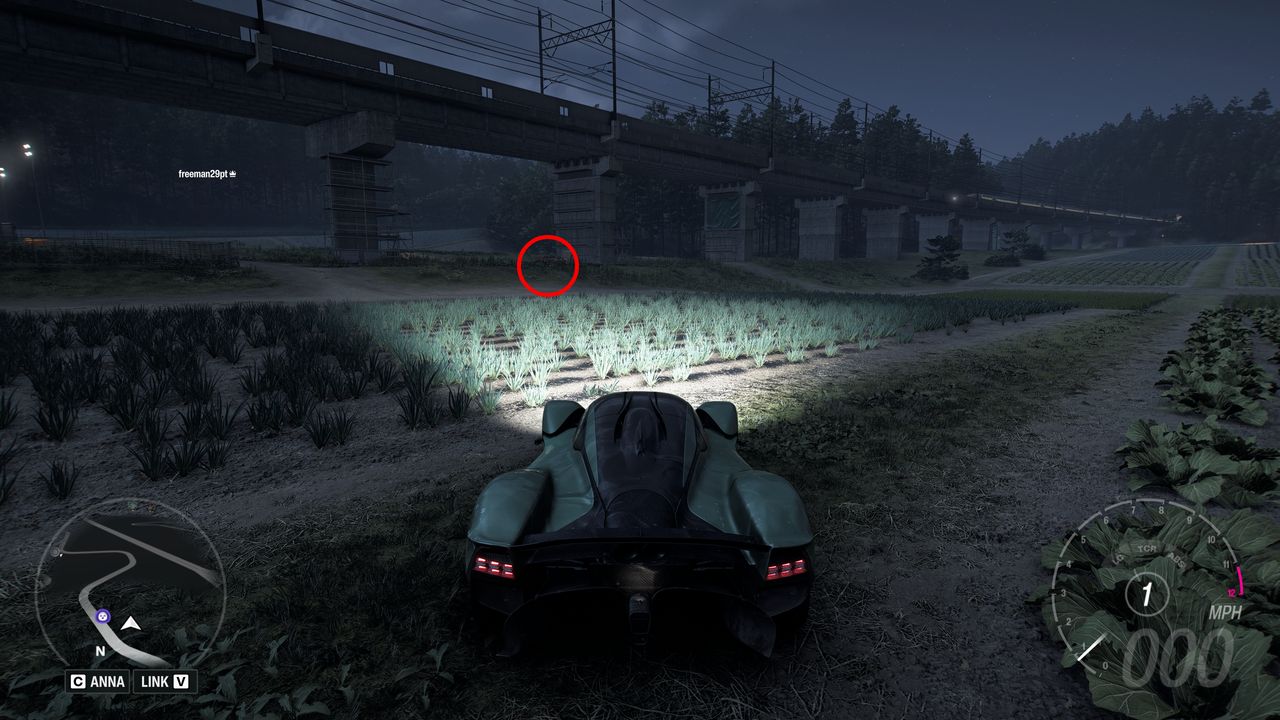 Forza Horizon 6 Treasure Cars: A player parked in a field looking at a railway bridge at night, with a red circle showing the location of the BMW M1.