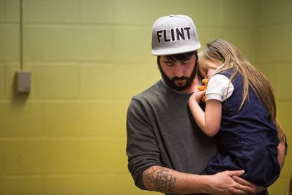 A father comforts his daughter after her free lead screening on Jan. 26, 2016.