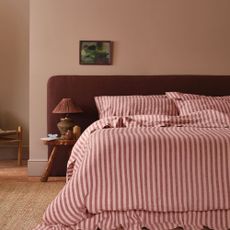 Pink bedroom with large headboard and linen bed sheets