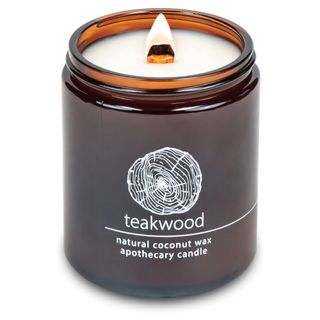 A lit brown glass teakwood candle