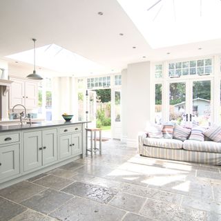 orangery with two skylights and glazed walls feautring a white kitchen and sofa