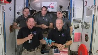 NASA astronaut Bob Behnken displays Tremor the apatasaurus, a toy dinosaur that he and Doug Hurley brought with them on SpaceX's Demo-2 Crew Dragon test flight to serve as a weightless indicator, during a farewell ceremony on the International Space Station Aug. 1, 2020.