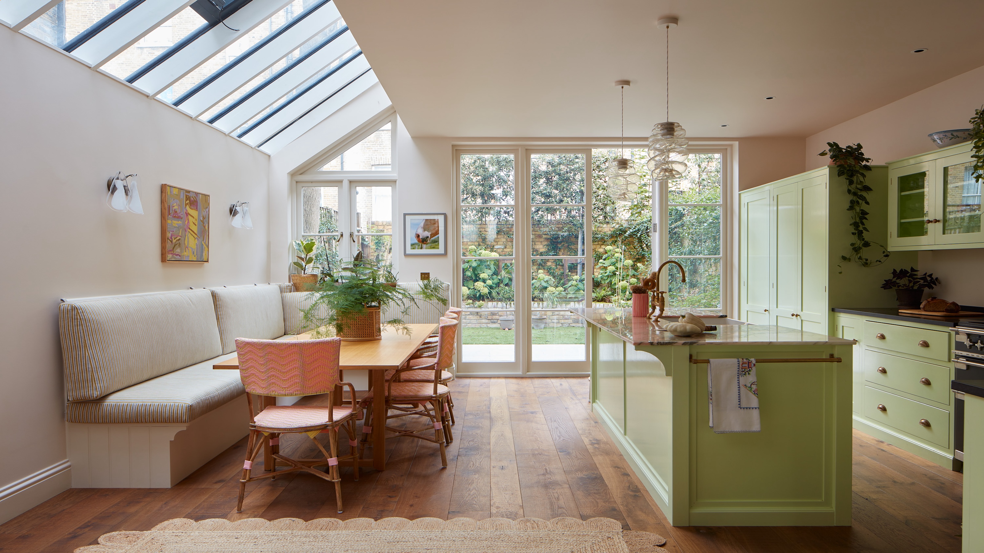 a light filled green kitchen showing patio doors to the garden and a series of roof lights to let the light flood in