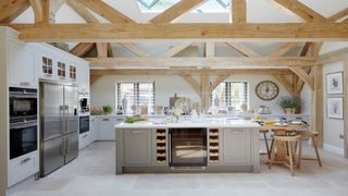 Kitchen island in middle of modern kitchen with exposed trusses and wood furniture