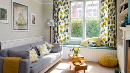 living room with grey wall window seat and grey sofa with cushion and tea table 