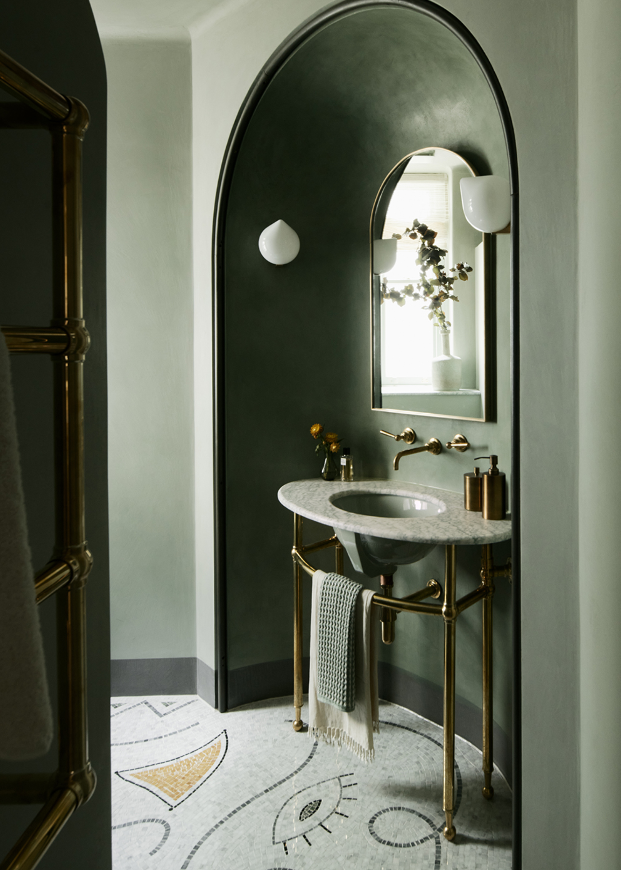 green bathroom with mosaic floor and a sink in the middle
