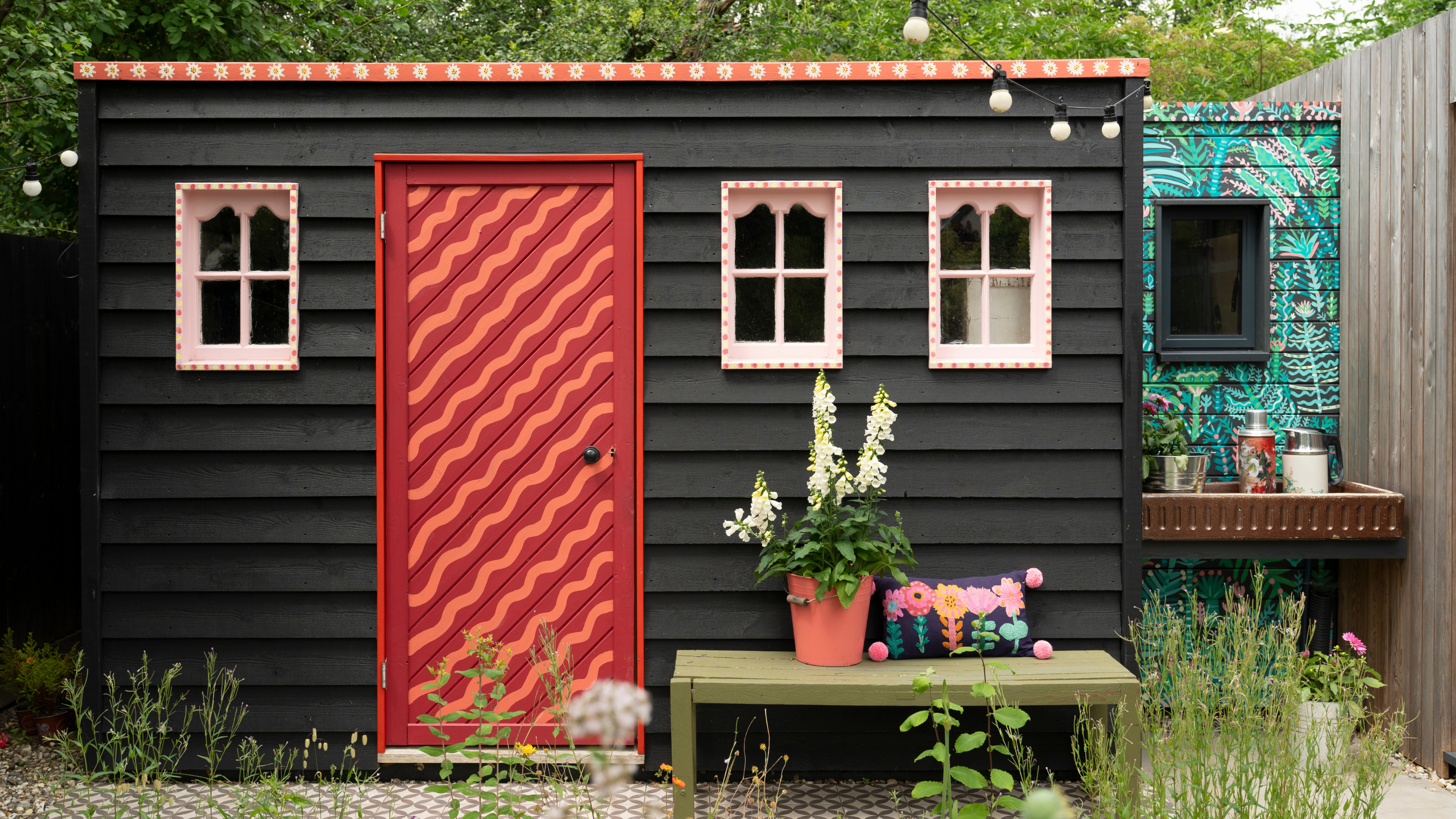 Black shed with red striped front door.