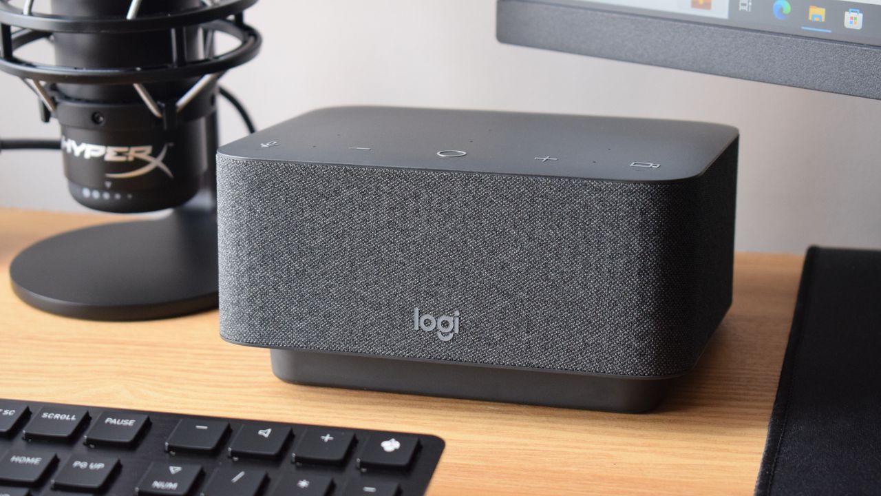 Photo of the Logitech Logi Dock docking station as part of a setup, powering a wired HyperX microphone, a CHERRY keyboard, and an external MSI monitor.