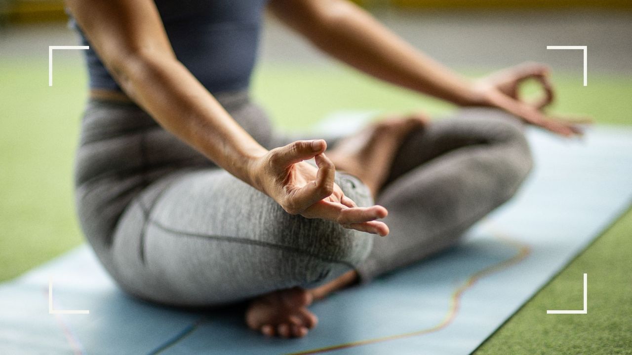 Woman sitting down on yoga mat in resting pose, trying to lose weight with yoga